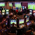 Exciting sports betting experience at ManClub, featuring lively patrons engaging with betting apps and screens.